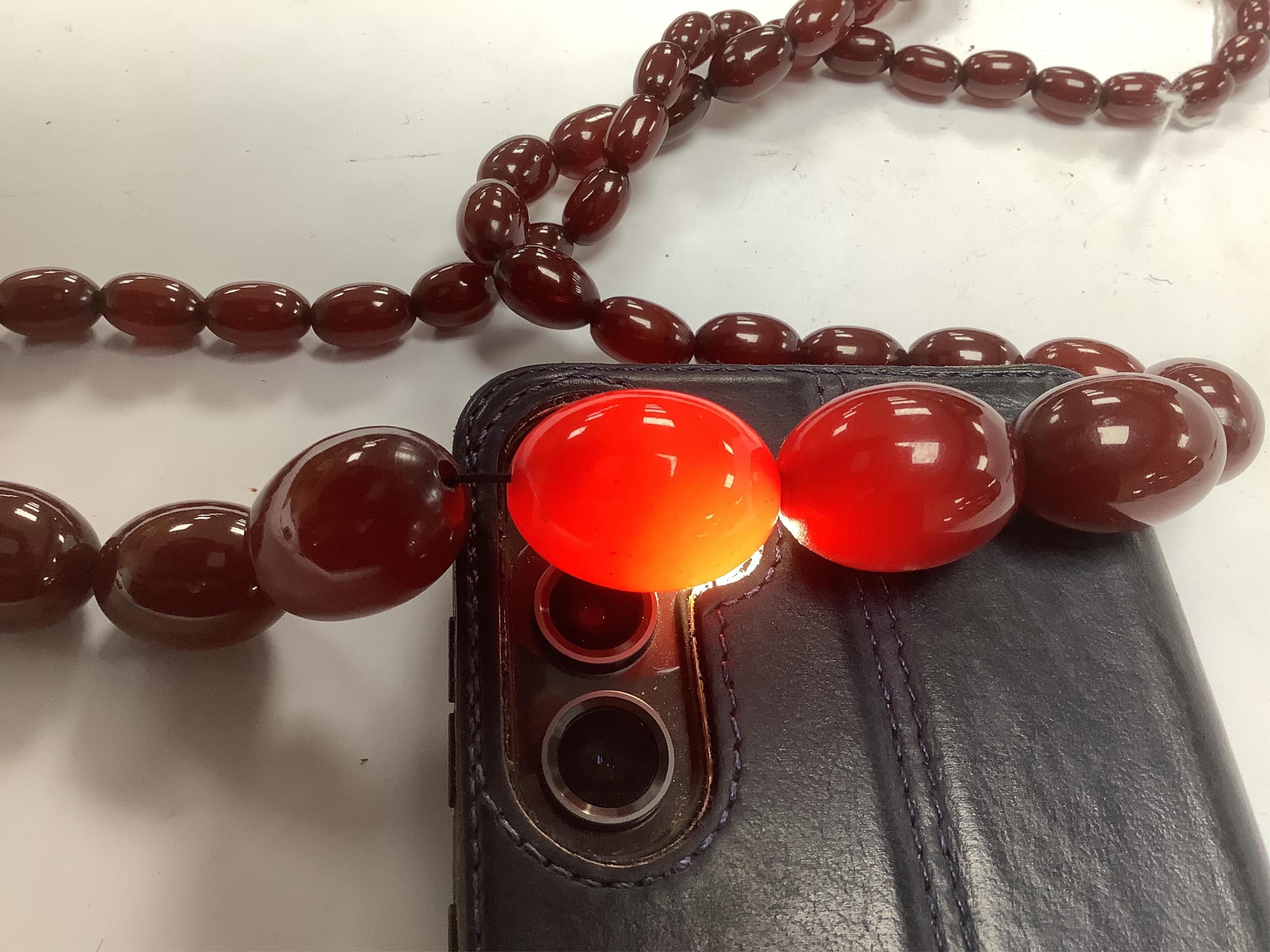 A single strand graduated oval simulated cherry amber bead necklace, 74cm, gross weight 71 grams. Condition - fair